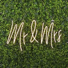 the word mr and mrs written in white neon lights on top of a green wall