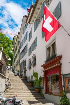 a red and white flag hanging from the side of a building next to a motorcycle