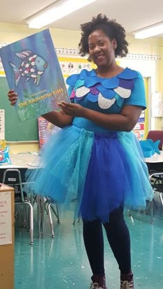 a woman in a blue dress is holding a book