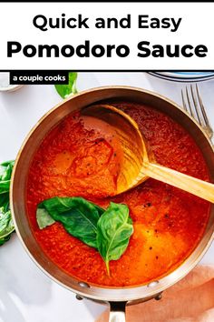 a pot filled with red sauce and basil leaves