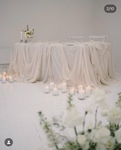 the table is set with candles and flowers in vases on the floor next to it