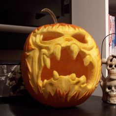 a carved pumpkin sitting on top of a table next to a small skeleton figurine