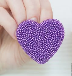 a purple beaded heart being held by someone's hand