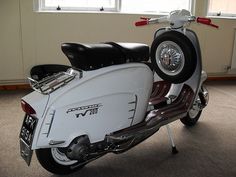 a white scooter parked in a room next to a window