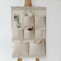 a canvas bag hanging on a wooden easel with eyeglasses and other items in it