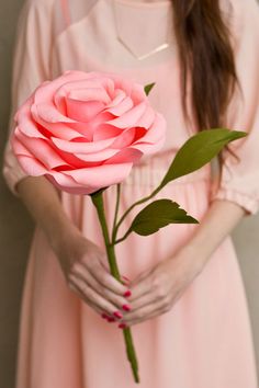 a woman holding a pink rose in her hands