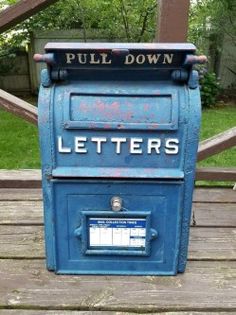 a blue mailbox sitting on top of a wooden deck