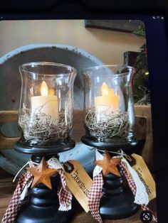 two glass candles are sitting on top of a wooden box with twine ribbons around them