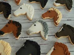 decorated cookies in the shape of horses are arranged on a white wooden table with brown and black icing