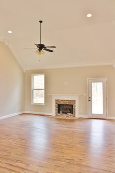 an empty living room with hard wood floors and a ceiling fan in the middle of the room