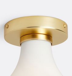 a close up of a light fixture on a white wall with a gold ring around it