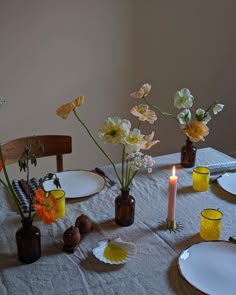 the table is set with plates and vases filled with flowers, candles and napkins