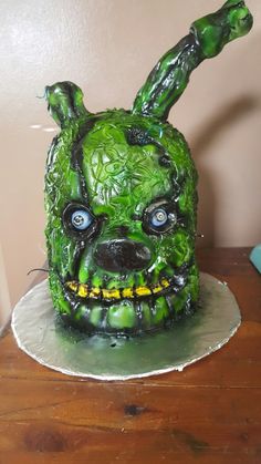 a green mask with blue eyes on top of a wooden table