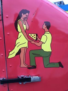 a man kneeling down next to a woman with a slice of pizza in her hand