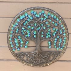 a metal tree with blue and green lights in the shape of a circle on a wall