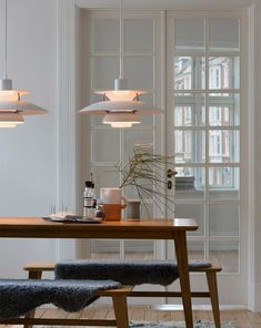 a dining room table with two chairs and some lights