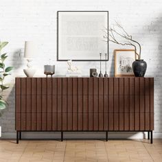 a white brick wall with a wooden dresser in the middle and pictures on top of it