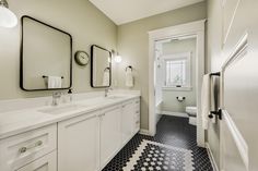 a bathroom with black and white flooring and two mirrors on the wall above the sinks