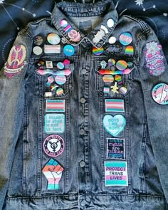 A dark grey denim jacket adorned with patches and pin badges with transgender, bisexual, nonbinary and gay themes down the front of the jacket, on the pockets, on the lapel and on the shoulders. Pride Battle Jacket, Battle Jackets Punk, Battle Pants, Patches Outfit, Emo Denim Jacket, Jean Jacket With Pins Outfits, Battle Clothes, Diy Punk Jeans