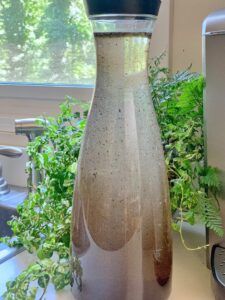 a glass bottle sitting on top of a counter next to a plant