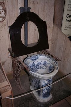 an old toilet with blue and white designs on the seat is in a display case