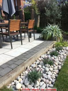 a patio area with chairs, tables and plants on the side walk in front of it