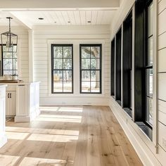 an empty room with wood floors and white walls, windows in the wall and cabinets on either side