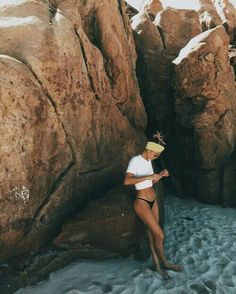 a woman standing in the water next to large rocks