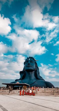 a large blue buddha statue sitting on top of a cement field