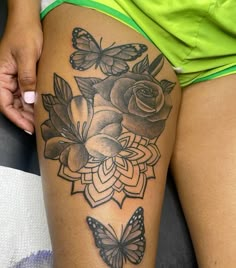 a woman's thigh with flowers and butterflies on her leg, next to a green shirt