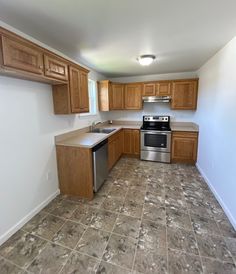 an empty kitchen with wood cabinets and stainless steel appliances in the middle of the room