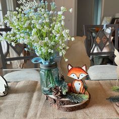 a vase filled with white flowers sitting on top of a wooden table next to a mason jar