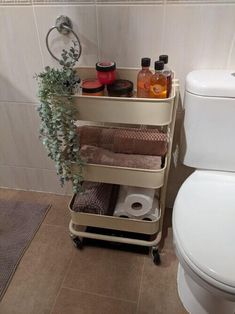 a bathroom with a toilet next to a shelf filled with towels and other items on it