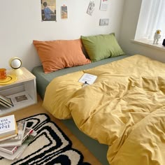 a bed sitting in a bedroom next to a window with lots of pillows on top of it