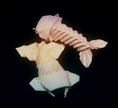 two origami fish on black background one is white and the other is pink