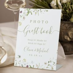 there is a sign that says photo guestbook on it next to a vase with flowers