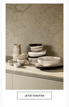 a counter topped with lots of white plates and bowls