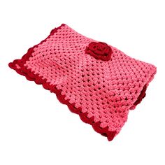 a pink crocheted pillow with a rose on it's side and a red flower in the middle