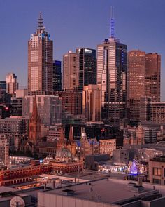 the city skyline is lit up at night, with tall buildings in the foreground