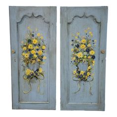 two blue doors with yellow flowers painted on them, one has a bow and the other has a wreath