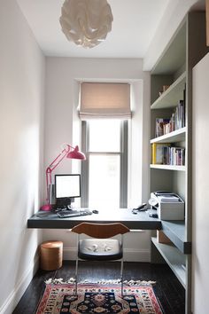 a room with a desk, chair and bookshelf next to a large window