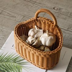 a basket filled with garlic sitting on top of a piece of paper next to a plant