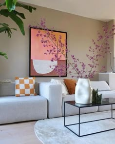 a living room with white furniture and purple flowers on the wall