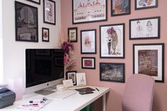 a home office with pink walls and pictures on the wall