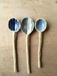 three wooden spoons sitting on top of a table next to each other with blue and white designs