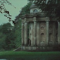 an old building sitting in the middle of a forest next to a body of water