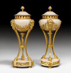 two golden and white vases sitting next to each other