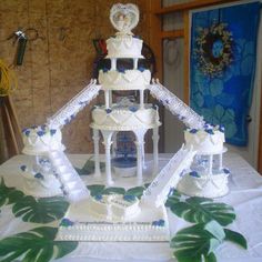 a white wedding cake on top of a table covered in blue and white decorations with leaves