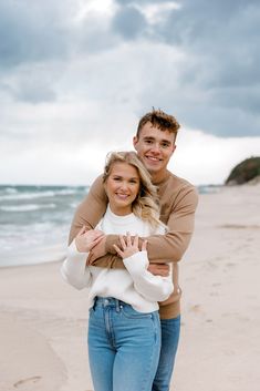 a man and woman are hugging on the beach