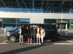 a group of people standing in front of a black van with their arms around each other